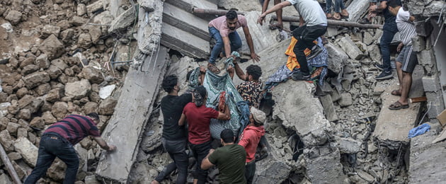 People carry a dead body pulled from rubble as civil defense teams and residents continue search and rescue efforts in the historical Greek Orthodox Saint Porphyrius Church, where civilians took shelter, after Israeli airstrike in Gaza City, Gaza on October 20, 2023.