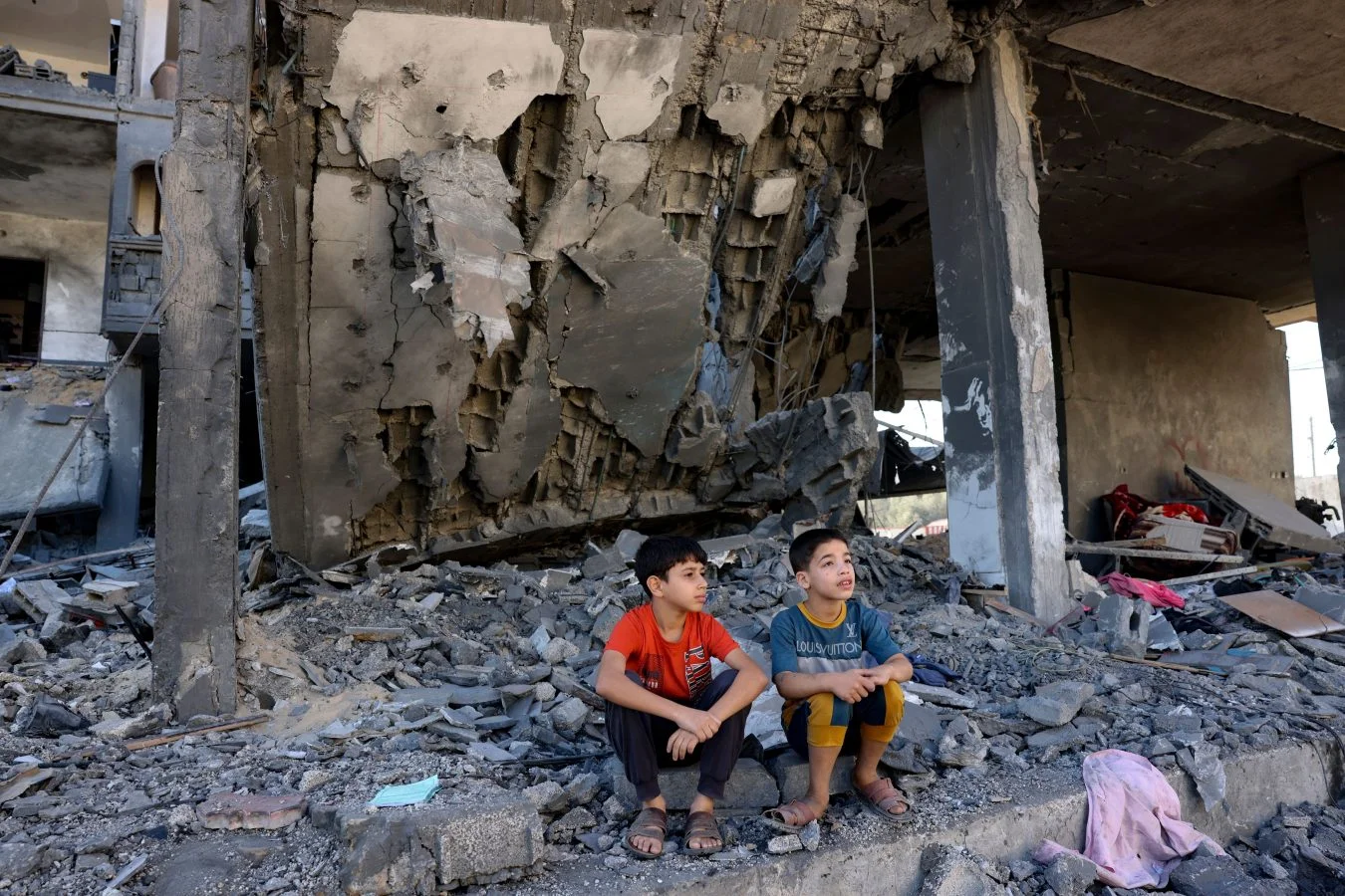 Two children sit on the floor of a destroyed building in Gaza during the Israel/OPT conflict, November 2023.