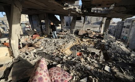 A man stands in the ruins of a skyrise apartment overlooking Gaza.