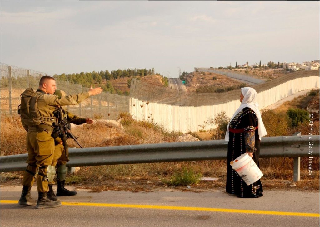 A Palestinian woman stands with others (not pictured) as they gather near an Israeli army checkpoint.