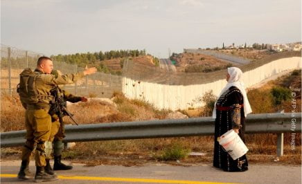 A Palestinian woman stands with others (not pictured) as they gather near an Israeli army checkpoint.