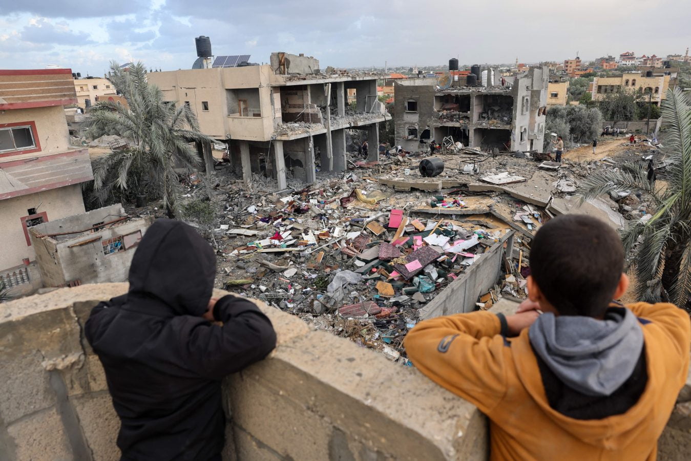 Palestinian children look on as people stand on the rubble of a building destroyed during Israeli strikes on Rafah, on the southern Gaza Strip, on November 20, 2023, amid continuing battles between Israel and Hamas.