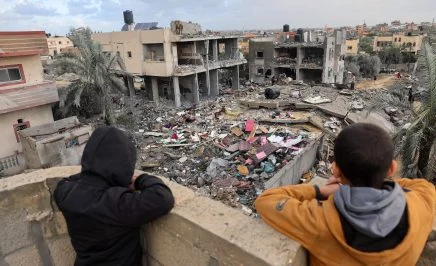 Palestinian children look on as people stand on the rubble of a building destroyed during Israeli strikes on Rafah, on the southern Gaza Strip, on November 20, 2023, amid continuing battles between Israel and Hamas.