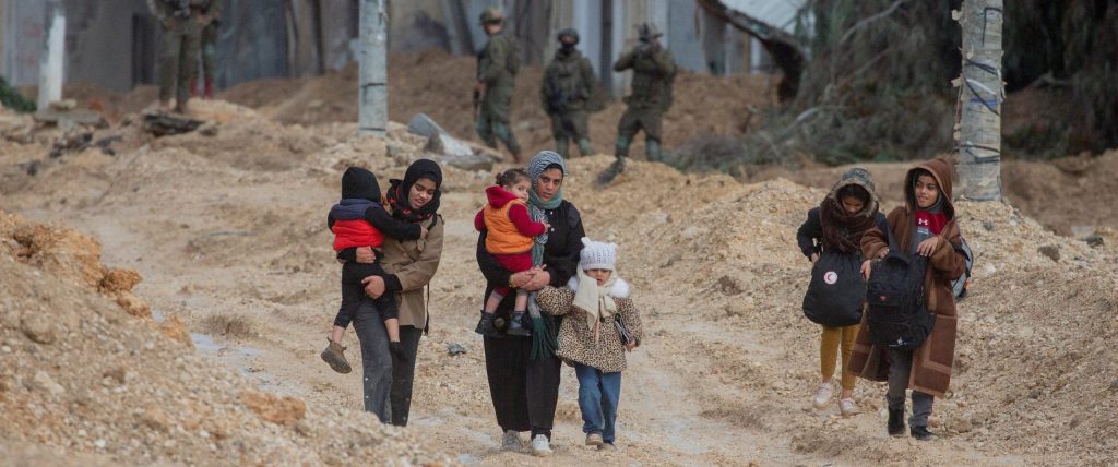A group of women and children walk along a muddy path in Nur Shams refugee camp on February 10, 2025. Heavy rains have worsened conditions in the camp, already struggling with displacement and limited infrastructure.