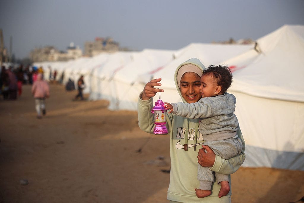 A girl shows a traditional lantern to a toddler, ahead of the iftar fast-breaking meal during the Muslim holy month of Ramadan, at a displacement camp at the Bureij refugee camp in the central Gaza Strip on March 5, 2025. (Photo by Eyad BABA / AFP) (Photo by EYAD BABA/AFP via Getty Images)